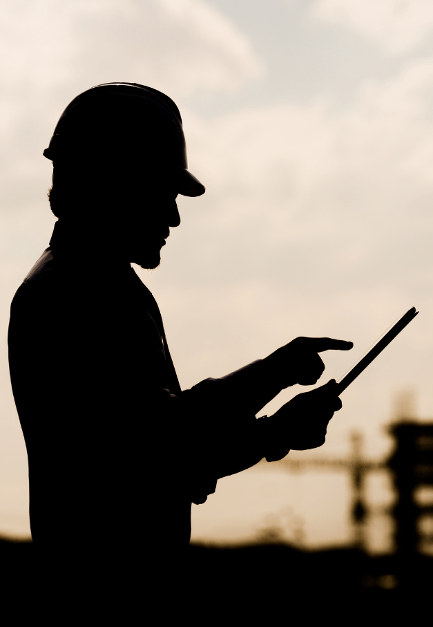 silhouette of a man in hardhat with ipad